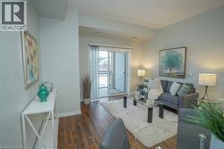 Living area featuring wood-finish flooring, light-toned walls, and a sliding glass door opening to an outdoor balcony - 