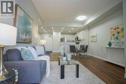 Open-concept living space with wood-finish flooring, recessed lighting, and a white kitchen featuring stainless steel appliances - 