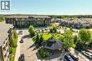 Modern multi-story residential building with balconies, surrounded by paved parking areas and green spaces - 7 Kay Crescent Unit# 107, Guelph, ON 