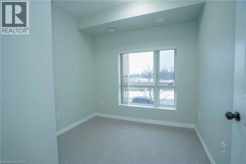 Room featuring a large multi-pane window, light-colored carpeting, white baseboards, and neutral wall paint - 7 Kay Crescent Unit# 107, Guelph, ON 