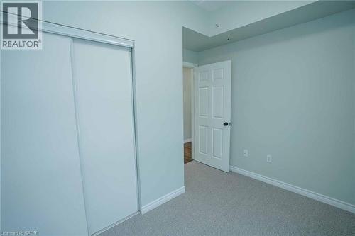 Bedroom featuring light-toned walls, white baseboards, and neutral carpet flooring - 7 Kay Crescent Unit# 107, Guelph, ON 