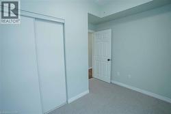 Bedroom featuring light-toned walls, white baseboards, and neutral carpet flooring - 