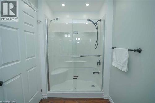 Shower enclosure with clear glass doors and black fixtures, featuring an integrated seating bench and shelving - 7 Kay Crescent Unit# 107, Guelph, ON 