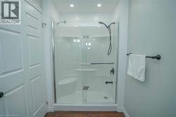 Shower enclosure with clear glass doors and black fixtures, featuring an integrated seating bench and shelving - 