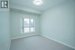 Carpeted room with a large window, light-toned walls, and a ceiling-mounted light fixture - 