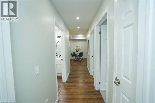 Hallway featuring wood-finish flooring, recessed lighting, white paneled doors, light gray wall paint, and white trim - 7 Kay Crescent Unit# 107, Guelph, ON 