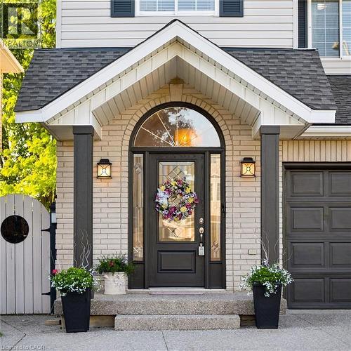 Brick facade entryway featuring an arched transom window above a panel glass front door, flanked by two exterior wall sconces - 214 Grey Fox Drive, Kitchener, ON 