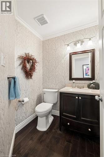 Compact bathroom featuring wood-finish flooring, a dark wood vanity with a light-colored countertop, and a white toilet - 214 Grey Fox Drive, Kitchener, ON 