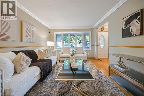 Bright living area featuring a bay window, crown molding, chair rail detailing, wood-finish flooring, and a decorative front entry door with an oval glass insert - 124 Dunsmere Drive, Kitchener, ON - Indoor Photo Showing Living Room
