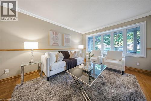 Bright living space featuring a large bay window, crown molding, two-tone wall treatment, and wood-finish flooring - 124 Dunsmere Drive, Kitchener, ON - Indoor Photo Showing Living Room