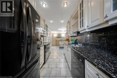 Galley kitchen featuring light-toned cabinetry with glass-front accents, dark speckled countertops, and a coordinating backsplash - 124 Dunsmere Drive, Kitchener, ON - Indoor Photo Showing Kitchen With Double Sink With Upgraded Kitchen