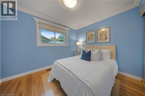 Bedroom featuring wood-finish flooring, a double-pane window, white crown molding, white baseboards, and a flush-mount ceiling light - 124 Dunsmere Drive, Kitchener, ON - Indoor Photo Showing Bedroom