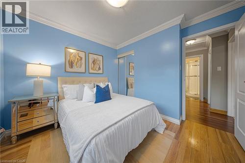 Hardwood flooring and crown molding in a room featuring a mirrored closet - 124 Dunsmere Drive, Kitchener, ON - Indoor Photo Showing Bedroom