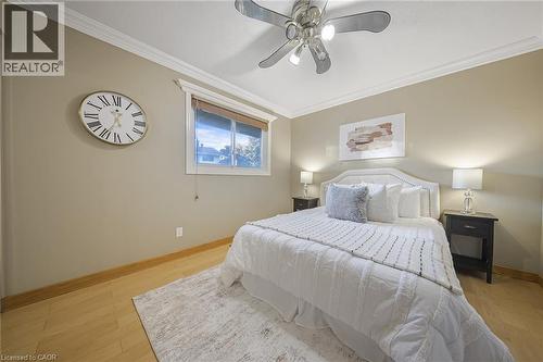 Neutral-toned bedroom featuring wood-finish flooring, a window with blinds, and crown molding - 124 Dunsmere Drive, Kitchener, ON - Indoor Photo Showing Bedroom