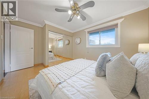 Bedroom featuring light-tone wood-finish flooring, a ceiling fan with integrated lighting, crown molding, and a window with blinds - 124 Dunsmere Drive, Kitchener, ON - Indoor Photo Showing Bedroom
