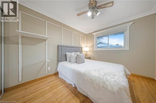 Room featuring wood-finish flooring, a window with window treatments, crown molding, and a ceiling fan with integrated lighting - 124 Dunsmere Drive, Kitchener, ON - Indoor Photo Showing Bedroom