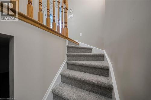 Staircase featuring light gray carpeting, crisp white trim, and a wood-finish handrail with turned balusters - 124 Dunsmere Drive, Kitchener, ON - Indoor Photo Showing Other Room