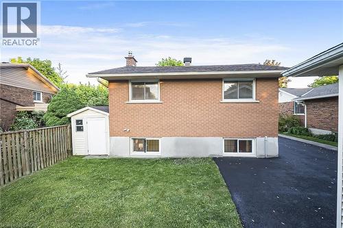 Expansive backyard featuring a manicured lawn, wood privacy fence, and a convenient storage shed - 124 Dunsmere Drive, Kitchener, ON - Outdoor With Exterior