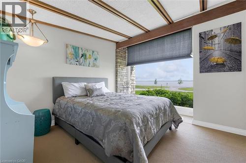 Expansive window overlooking a body of water, featuring a roller shade and a stone accent wall - 899 Niagara Parkway, Fort Erie, ON 