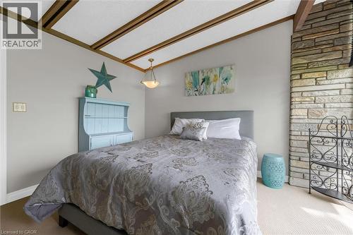 Vaulted ceiling with exposed wood beams, light fixture, stone accent wall, and neutral wall paint - 899 Niagara Parkway, Fort Erie, ON 