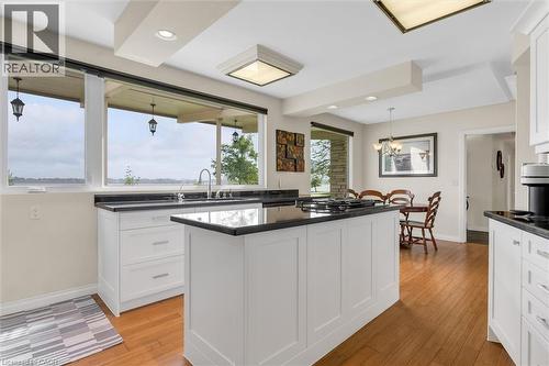 Kitchen featuring an integrated island, white cabinetry, dark countertops, and wood-finish flooring - 899 Niagara Parkway, Fort Erie, ON 