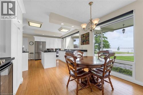 Open-concept kitchen featuring white cabinetry, stainless steel appliances, dark countertops, and wood-finish flooring - 899 Niagara Parkway, Fort Erie, ON 