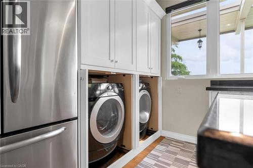 Built-in laundry appliances with cabinetry, a stainless steel refrigerator, dark countertop, and large window - 899 Niagara Parkway, Fort Erie, ON 