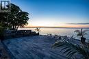 Expansive waterside patio featuring rectangular paver stones, a natural stone retaining wall, and mature trees - 6 Firelane 11A Street, Niagara-On-The-Lake, ON  - Outdoor With Body Of Water With View 