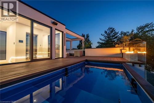 Outdoor swimming pool with integrated fire feature, surrounded by composite wood decking - 6 Firelane 11A Street, Niagara-On-The-Lake, ON - Outdoor With In Ground Pool With Deck Patio Veranda