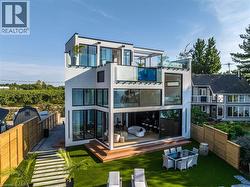 Contemporary multi-story residence featuring expansive glass panels, multiple outdoor terraces with glass railings, and a ground-level deck with artificial turf - 