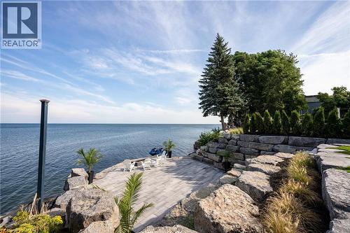 Waterfront patio with stone retaining walls, expansive paver surface, and mature landscaping - 6 Firelane 11A Street, Niagara-On-The-Lake, ON - Outdoor With Body Of Water With View
