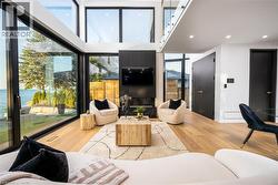 Expansive living area featuring soaring ceilings and oversized windows offering water scenery - 