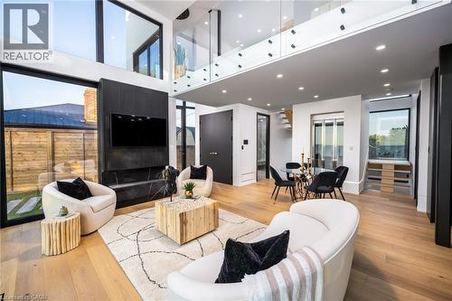 Double-height living space featuring expansive windows, a black accent wall with a built-in television, and a black marble-style fireplace - 6 Firelane 11A Street, Niagara-On-The-Lake, ON - Indoor Photo Showing Living Room