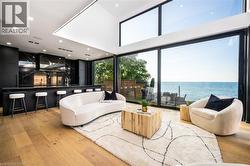Open-concept living space with expansive floor-to-ceiling windows overlooking a water feature - 