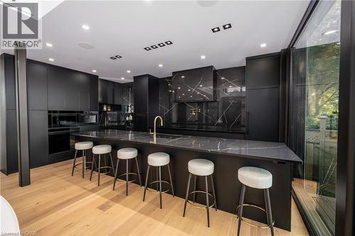 Modern kitchen featuring a large waterfall-edge island, matte black cabinetry, and light wood-finish flooring - 6 Firelane 11A Street, Niagara-On-The-Lake, ON - Indoor
