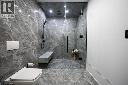 Walk-in shower featuring a frameless glass enclosure, dark-finish shower fixtures, and a built-in stone bench - 6 Firelane 11A Street, Niagara-On-The-Lake, ON - Indoor Photo Showing Bathroom