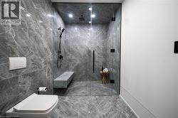 Walk-in shower featuring a frameless glass enclosure, dark-finish shower fixtures, and a built-in stone bench - 