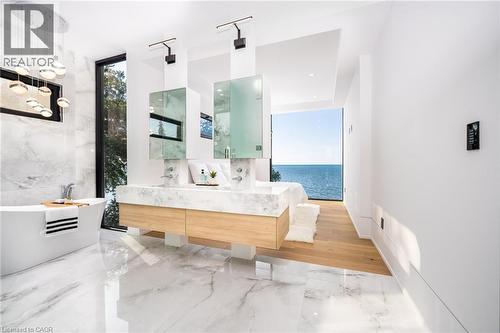 Contemporary bathroom featuring a freestanding soaking tub, dual vanity with undermount sinks, and a full-height window overlooking a body of water - 6 Firelane 11A Street, Niagara-On-The-Lake, ON - Indoor Photo Showing Bathroom