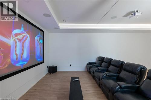 Dedicated media room featuring a large projection screen, mounted projector, recessed ceiling lighting, integrated ceiling speakers, and wood-finish flooring - 6 Firelane 11A Street, Niagara-On-The-Lake, ON - Indoor