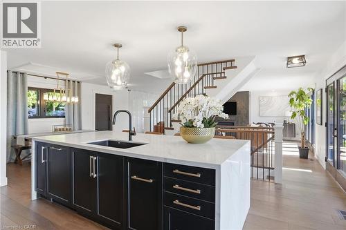 Spacious kitchen island featuring a white countertop, undermount sink, matte black faucet, and dark cabinetry with brass-tone hardware - 71 Miles Road, Hamilton, ON 