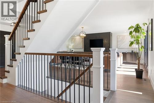 Staircase featuring wood-finish treads, a dark wood-finish handrail, and black metal balusters - 71 Miles Road, Hamilton, ON 
