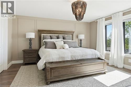 Spacious room featuring wood-finish flooring, a decorative ceiling fixture, and wall paneling - 71 Miles Road, Hamilton, ON 