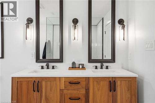 Dual wood-finish vanity with integrated sinks, quartz countertop, and matte black fixtures - 71 Miles Road, Hamilton, ON 