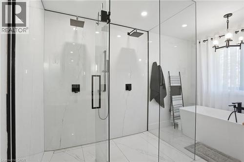 Modern bathroom featuring a spacious glass-enclosed shower with dual rain showerheads and matte black fixtures - 71 Miles Road, Hamilton, ON 