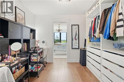 Walk-in closet featuring light wood-finish flooring, white walls, and built-in closet systems with shelving and drawers - 71 Miles Road, Hamilton, ON 
