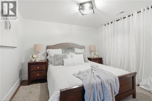 Recessed lighting fixture illuminating a room featuring wood-finish flooring, white walls, and white curtains - 71 Miles Road, Hamilton, ON 