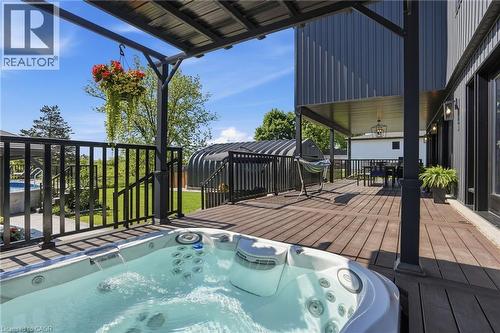 Expansive outdoor deck featuring a hot tub, shaded patio area, and dark wood-finish flooring - 71 Miles Road, Hamilton, ON 