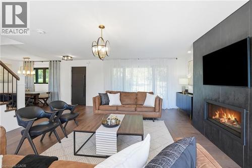 Spacious living area featuring wood-finish flooring, a contemporary fireplace with dark-toned tile surround, and an open layout - 71 Miles Road, Hamilton, ON 