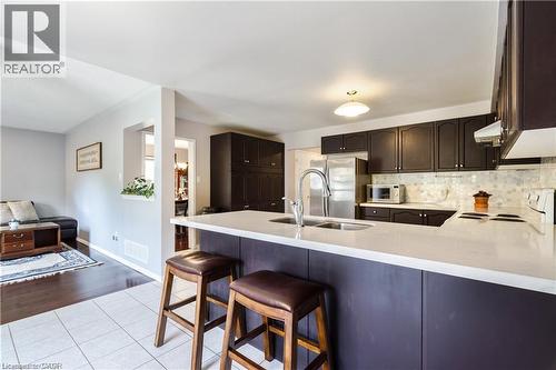 Kitchen featuring dark cabinetry, stainless steel appliances, white countertops, and a mosaic tile backsplash - 106 Moore Crescent, Ancaster, ON 