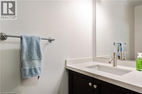 Bathroom vanity featuring a white countertop with an integrated rectangular sink, brushed nickel faucet, and dark wood-finish cabinetry with silver hardware - 106 Moore Crescent, Ancaster, ON 